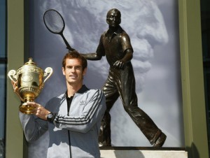 Tennis player Andy Murray of Britain holds the trophy under a statue of former British champion Fred Perry, at Wimbledon