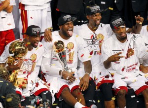 Heat's James holds the Bill Russell MVP Trophy as Wade (L) holds the Larry O'Brien Trophy while Bosh celebrates after their team defeated the Spurs in Game 7 to win their NBA Finals basketball playoff in Miami